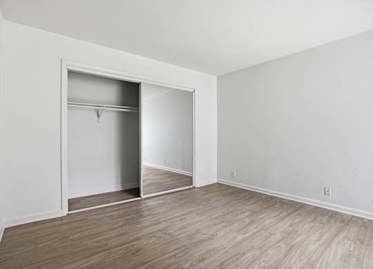 A room with a white wall and a white closet with a mirror.