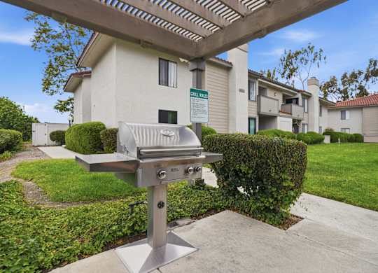 A barbecue grill is in the foreground of a residential area.