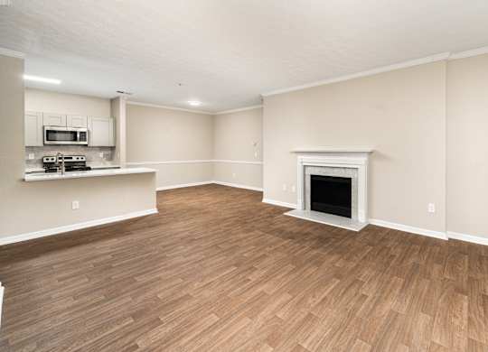 an empty living room with a fireplace and a kitchen