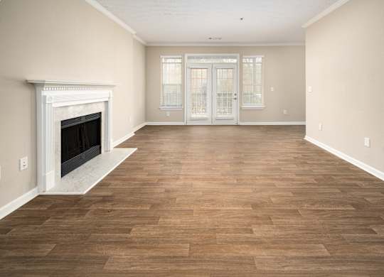 an empty living room with a fireplace and a wooden floor