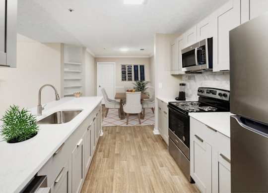 an open kitchen and living room with white cabinets and stainless steel appliances
