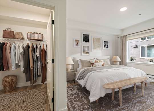 A bedroom with a bed, a bench, and a closet with clothes.