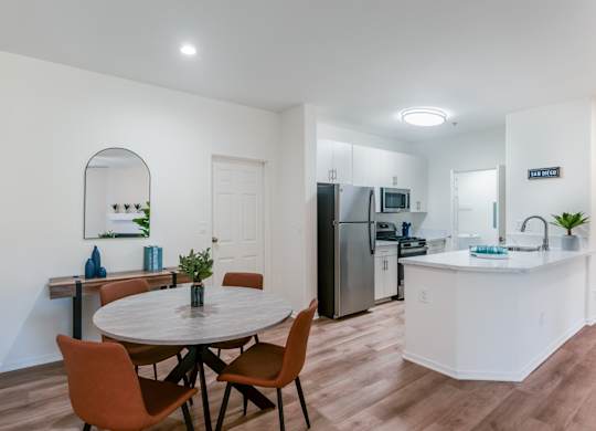 A kitchen with a table and chairs in the foreground and a refrigerator in the background.
