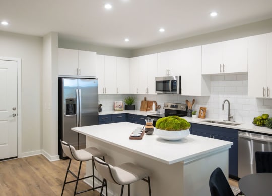 a kitchen with a white counter top and a stainless steel refrigerator