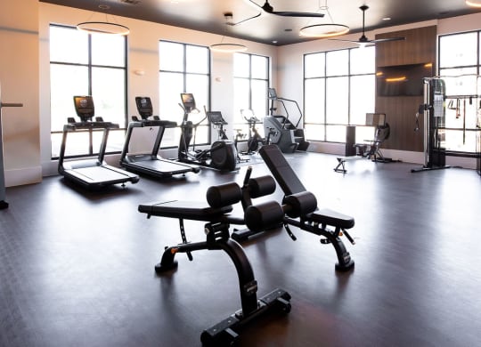 a fitness room with weights and chairs in it