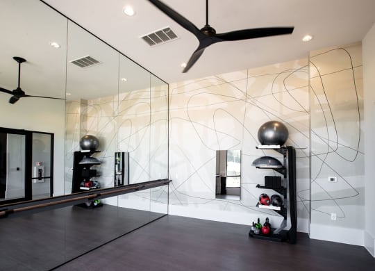 a home gym with mirrored walls and a ceiling fan
