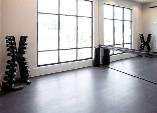 a workout room with a ceiling fan and dumbbells