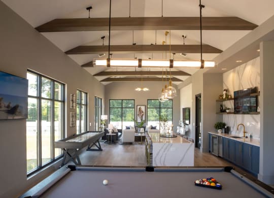 a pool table in the center of a living room with large windows