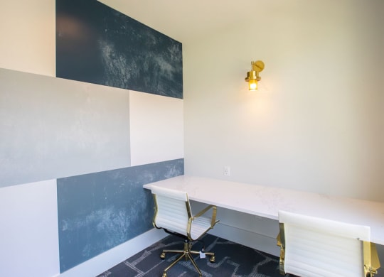 a desk and chair in a room with a wall and a lamp