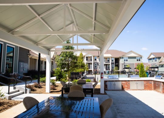 a covered patio with a table and chairs next to a pool