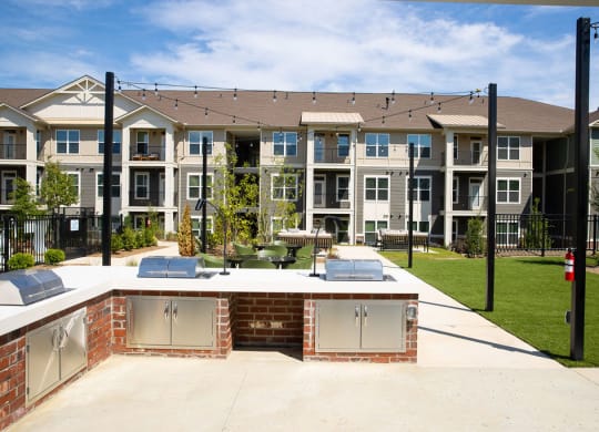 an outdoor entertaining area with a patio and lawn in front of an apartment building