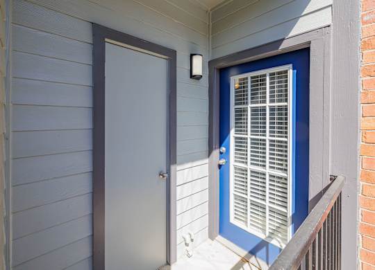 A blue door with a window is on the right side of a white wall at Clear Creek Meadows Apartments, Texas, 76522
