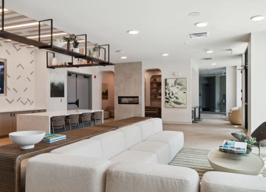 a living room with a long white couch and a bar