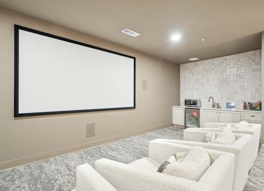 A modern living room with a large screen and comfortable seating.
