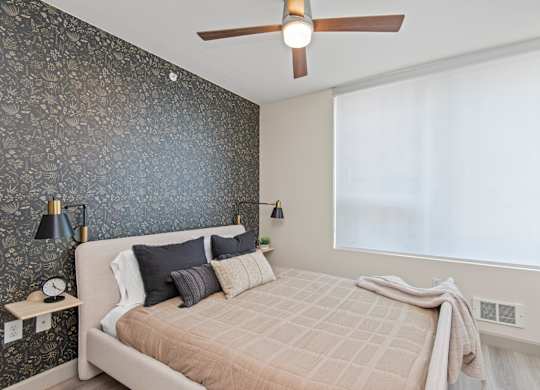 a bedroom with a dark accent wall and a ceiling fan