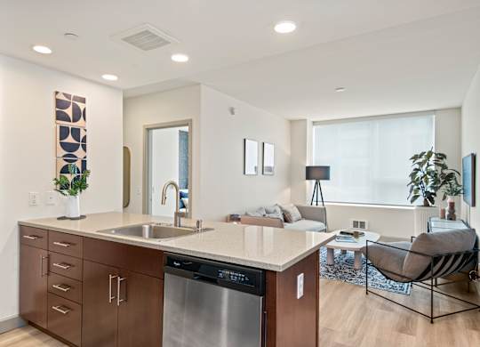 a kitchen with a large center island next to a living room with a couch and a window