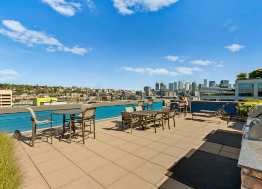 an outdoor terrace with tables and chairs with a city skyline in the background  at Dexter Lake Union, Seattle, WA, 98109