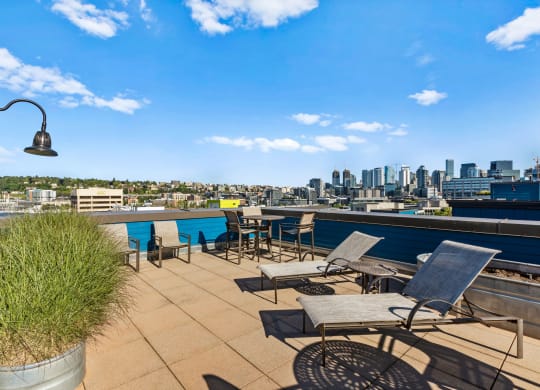a roof deck with lounge chairs and a table with a view of the city  at Dexter Lake Union, Seattle, Washington