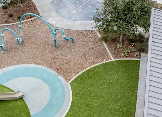 A playground with a slide and a green lawn. at The Village at Caney Mills, Conroe, Texas