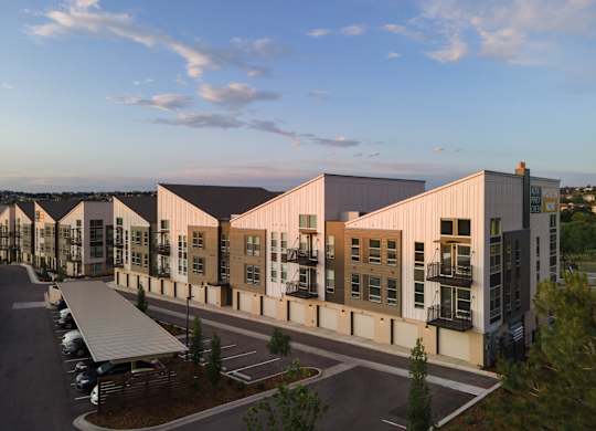 A modern building complex with a parking lot in front.