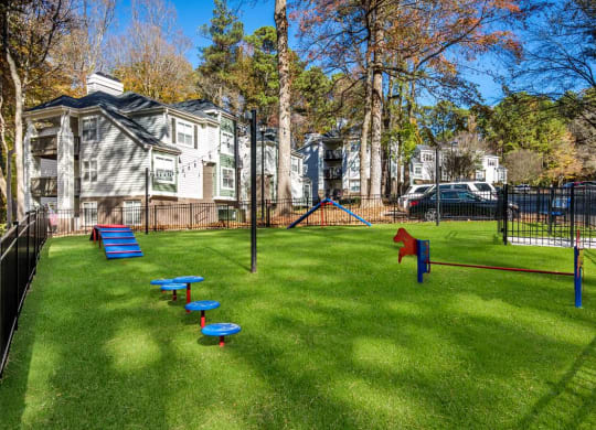 a grassy area with a playground and houses in the background