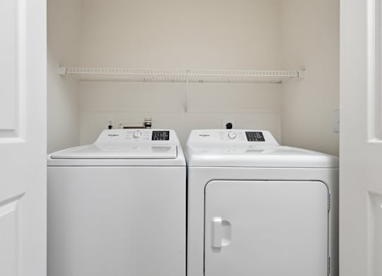 Two white front loading washing machines in a small laundry room.