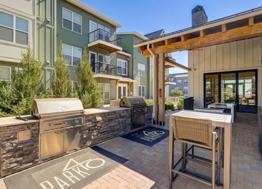 a patio with a grill and a bar with chairs