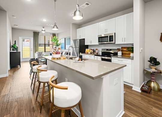 A kitchen with white cabinets and a large island with bar stools.