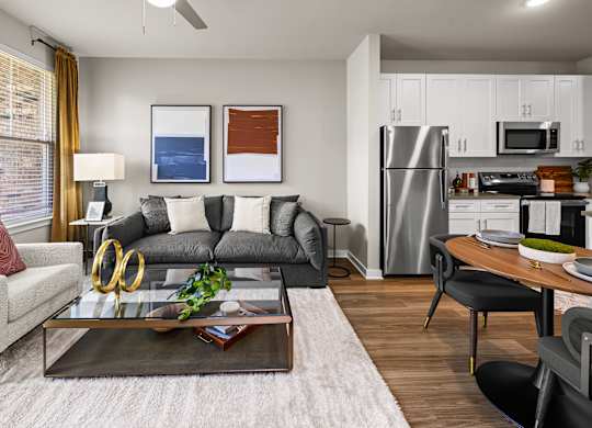 A modern living room with a grey sofa, a coffee table, and a kitchen in the background.