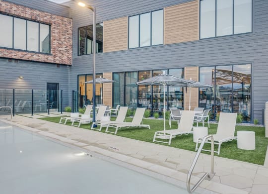 a row of lawn chairs and umbrellas in front of a building
