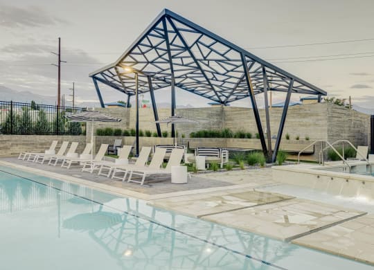 awning over a swimming pool with white lounge chairs