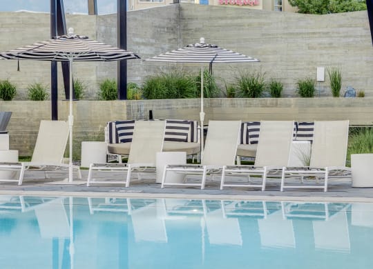a row of lounge chairs and umbrellas next to a pool