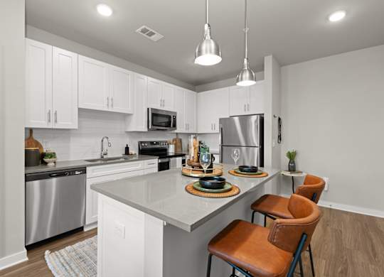 A modern kitchen with a center island and brown leather chairs.