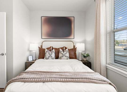 A bedroom with a large bed and a painting above it.