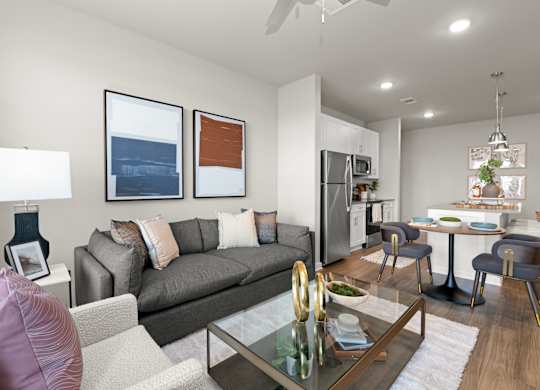 A modern living room with a grey couch and a glass coffee table.