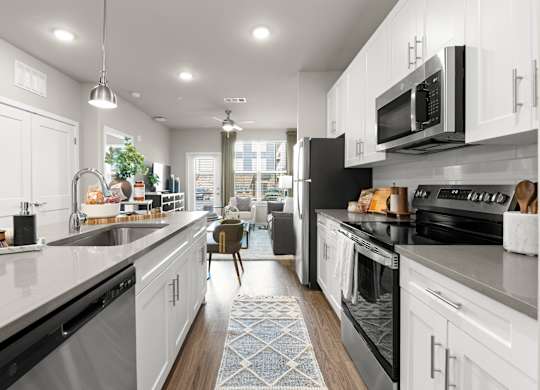 A modern kitchen with white cabinets and black appliances.