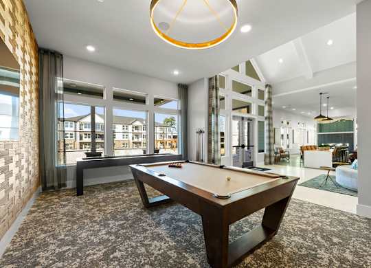 A pool table is in the middle of a room with a brick wall and a window.