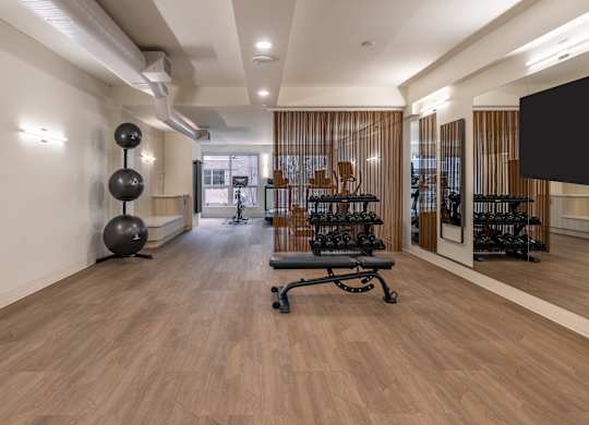 a room with a chair and a tv in the corner and a wood flooring