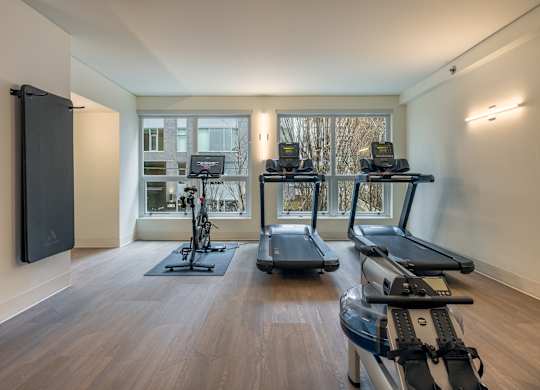 a gym with treadmills and weights and a tv