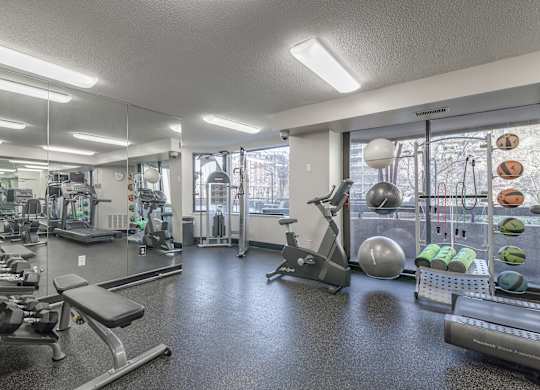 a gym with exercise equipment and weights on the floor and a mirrored wall