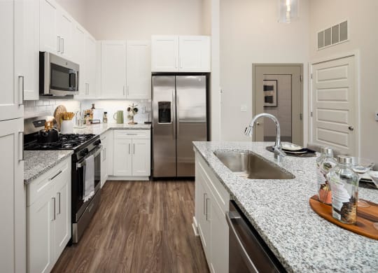 a kitchen with granite counter tops and a stainless steel refrigerator