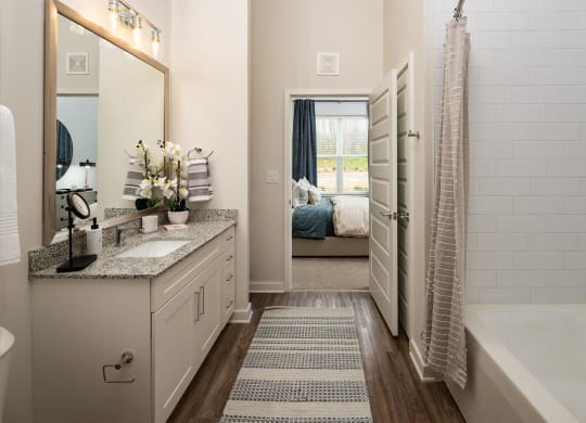 a bathroom with a shower and a sink and a door to a bedroom