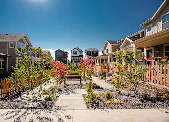 a group of houses with a walkway and benches in a garden