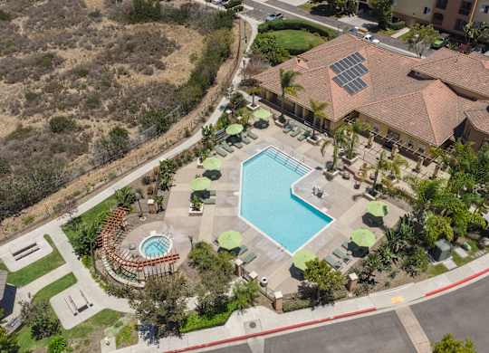 A large swimming pool surrounded by a grassy area and a building with a red roof.