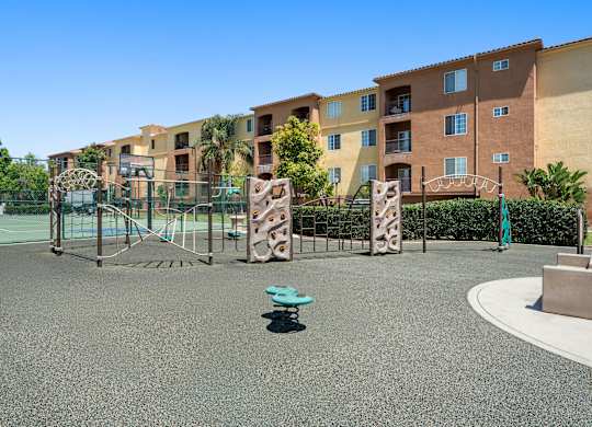 A playground with a blue bench in the middle of a grey ground.