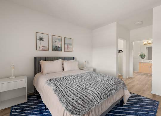 A bedroom with a bed, nightstand, and pictures on the wall.