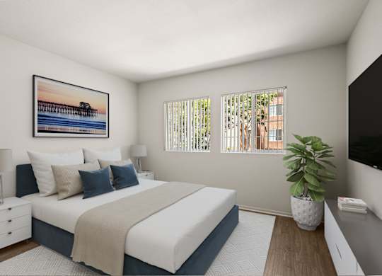 A bedroom with a large bed, a nightstand, a lamp, a potted plant, and a framed picture on the wall.