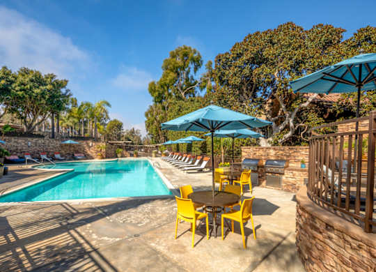 A pool area with a table and chairs and umbrellas.