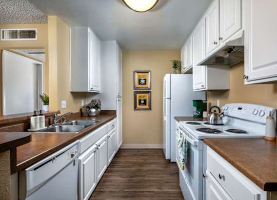 A kitchen with white cabinets and a fridge.