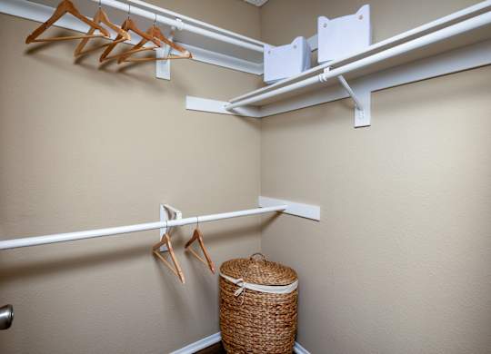 A white metal rod is mounted on a wall with clothes hangers and a basket underneath.